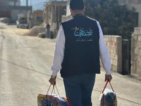 متطوع يحمل حقائب شتوية لتوزيعها
